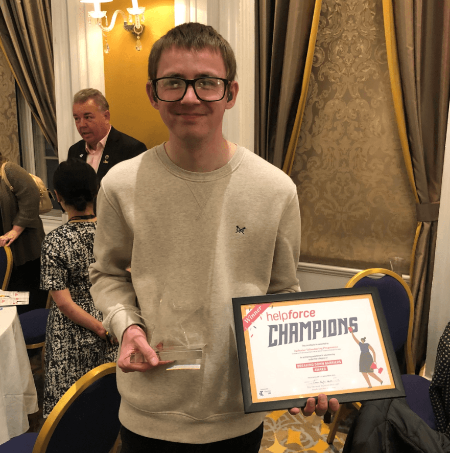 Matt Price, Inclusive Volunteer, holds the Helpforce Champion award and certificate