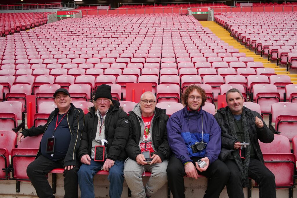The team sat in stadium seats, smiling.