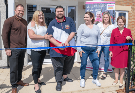 Ben, a person supported by Community Integrated Care, cuts the blue ribbon to mark the opening of Ashby Road, a new supported living service in Leicestershire.