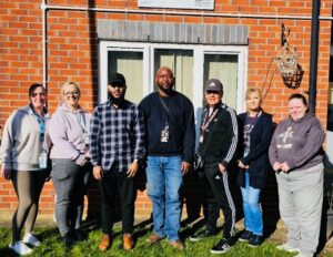 A group of colleagues from Somerset House, a care service in Tameside, stand and smile together